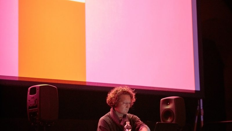 person playing eletronic music in front of visuals on a screen